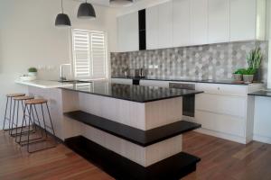 a kitchen with a black counter top and white cabinets at Caves Coastal Bar & Bungalows in Caves Beach