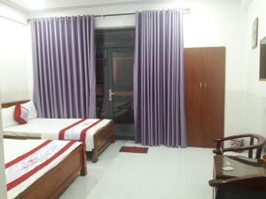 1 dormitorio con 2 camas y cortinas moradas en Anh Quân Hotel, en Quy Nhon