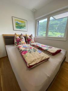 a bed with three pillows on it in a room with a window at Appartement Lukic in Kaprun