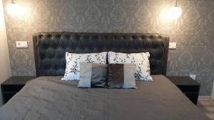 a bed with a black headboard and pillows on it at Jaukūs apartamentai-studija, centre in Šiauliai