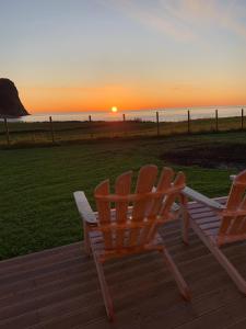 dos sillas sentadas en una terraza viendo la puesta de sol en Unstad Arctic Resort, en Unnstad
