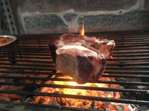 a piece of meat is cooking on a grill at A Lonquexa do Gañán in Gondomar
