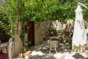 un patio con mesa, sombrilla y árboles en Petite Olive House, en Sitia