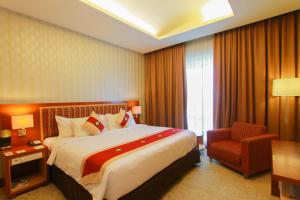 a hotel room with a large bed and a chair at Swiss-Belhotel Maleosan Manado in Manado