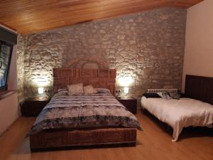 a bedroom with two beds and a stone wall at Casa rural Ca l'Antón in Sant Miquel de Campmajor +58 photos