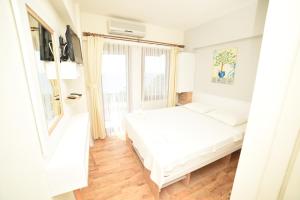 a white bedroom with a bed and a window at Limonata Hotel Assos in Behramkale