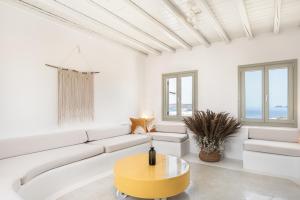 a white living room with a white couch and a yellow coffee table at Mykonos Unique Villas in Kalafatis