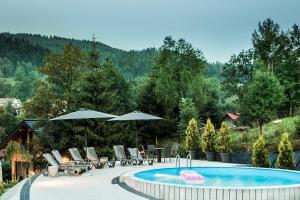 a pool with chairs and tables and umbrellas at Apartamenty Eskapada in Korbielów