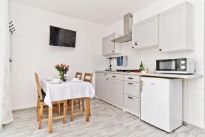a kitchen with white cabinets and a table with chairs at Apartamenty In Chałupy Kaperska in Chałupy +14 photos