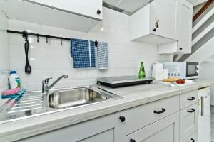 a kitchen with white cabinets and a sink at Apartamenty In Chałupy Kaperska in Chałupy