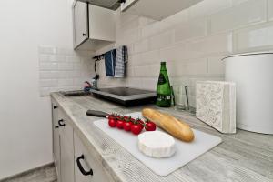a kitchen counter with a cutting board with cheese and tomatoes at Apartamenty In Chałupy Kaperska in Chałupy