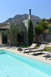 a pool with two lounge chairs and a house at Villa Lithos in Kymi