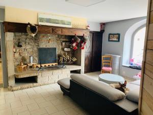 sala de estar con sofá y chimenea de piedra en Hôtel-Restaurant La Bergerie, en Sévérac d' Aveyron