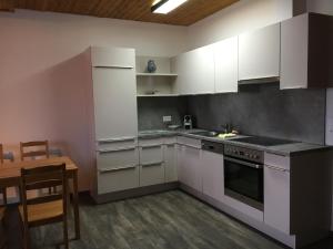 cocina con armarios blancos, mesa y mesa en Appartement Rietli en Triesenberg