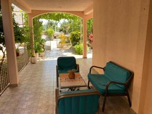 a porch with two chairs and a table with a cat on it at Guest House Andrea in Budva