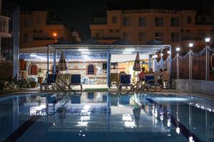 a swimming pool at night with people sitting at a restaurant at Sunset Village in Didim