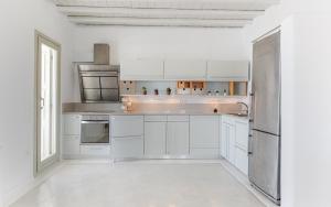 a kitchen with white cabinets and a stainless steel refrigerator at Mykonos Unique Villas in Kalafatis