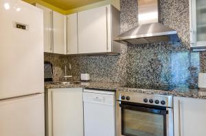 a kitchen with white cabinets and a stove top oven at Devesa Park Apartment with Private Parking in Girona