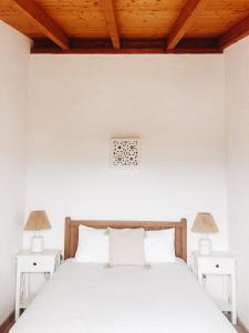 1 dormitorio con 1 cama blanca y 2 mesas blancas en Calma Aljezur, en Aljezur