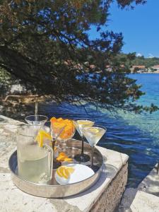 a tray with glasses of drinks on a table by the water at Apartmani Jagoda in Lastovo