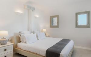 a bedroom with a white bed with two windows at Mykonos Unique Villas in Kalafatis +33 photos