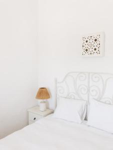 a white bedroom with a white bed and a lamp at Calma Aljezur in Aljezur