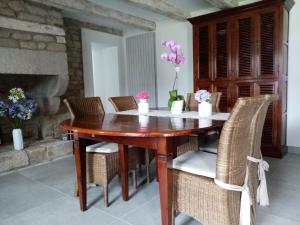 drewniany stół jadalny z krzesłami i kwiatami w obiekcie Entre terre et mer w mieście Ploemeur