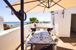 - une table avec un parasol sur le balcon donnant sur la plage dans l'établissement MalagadeVacaciones - El Pedregal, à Malaga