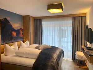 a bedroom with a large bed with a large window at Post Hotel Paznaun in See