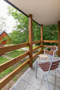 eine Veranda mit einem Holzzaun, einem Stuhl und einem Tisch in der Unterkunft Hotel Rusava chaty in Rusava