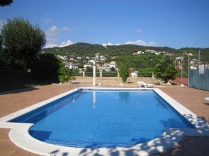a blue swimming pool with a mountain in the background at Hostal Los Pinares in Lloret de Mar