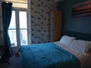 a bedroom with a bed with a blue blanket and a window at The Chequers in Great Yarmouth +16 photos