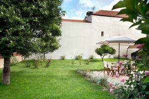 einen Garten mit einem Tisch und einem Sonnenschirm in der Unterkunft Chronis Family Villas in Krousón