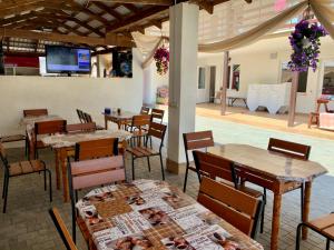 a dining room with tables and chairs and a television at Mirage Hotel in Zatoka