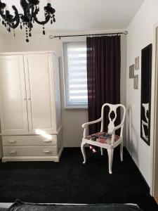 a room with a white chair and a dresser at Ferienwohnung FLAIR in Zella-Mehlis