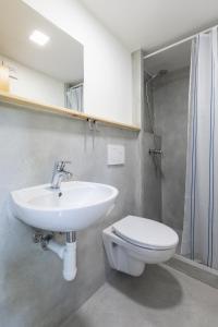 La salle de bains est pourvue d'un lavabo blanc et de toilettes. dans l'établissement Hotel Rusava chaty, à Rusava