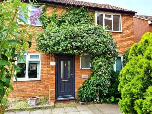 a brick house with a black door and ivy at Rayleigh House in Rayleigh