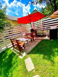 a patio with a red umbrella and a picnic table at Vinyl’s Place in Braşov