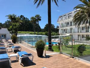 a hotel with a swimming pool and palm trees at Hotel Nuevo Vichona Spa 3 estrellas Superior in Sanxenxo