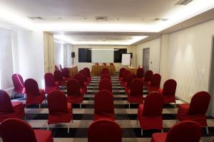 a conference room with red chairs and a podium at CROWN PRINCE Hotel Surabaya Managed by Midtown Indonesia in Surabaya