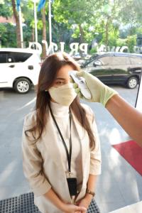 una mujer con una máscara facial y un guante en CROWN PRINCE Hotel Surabaya Managed by Midtown Indonesia, en Surabaya