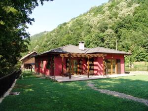 a small red house with a grass yard at Boyana Vacation Houses in Cherni Vit