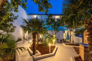 una casa con un patio con palmeras y luces en Apartments San Leopoldo, en Crikvenica