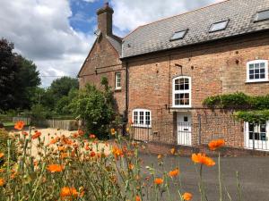 a brick house with a field of flowers in front of it at The Old Mill Bed and Breakfast in Bere Regis