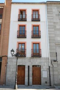 a white building with windows and balconies and a street light at San Vicente Apartments in Avila