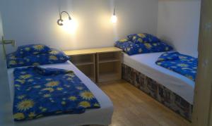 ヘーヴィーズにあるMadách Apartmanの青と黄色のシーツが備わる客室のベッド2台