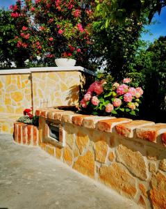 a brick wall with flowers on top of it at Apartmani Franciska in Rab