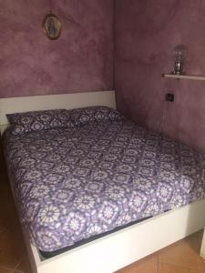 łóżko w sypialni z fioletową ścianą w obiekcie Casa Rosa w mieście Dervio