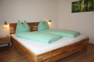 Una cama con almohadas verdes encima. en Ferienhaus Julia, en Admont