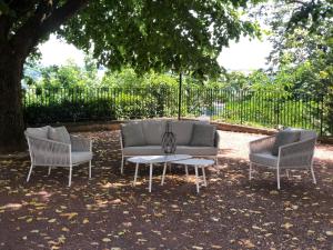 a couch and two chairs and a table under a tree at La Souveraine in Saint-Genis-Laval